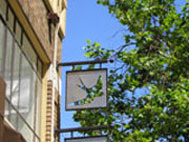 metal sign over shop with bird-shape hole, showing tree behind it